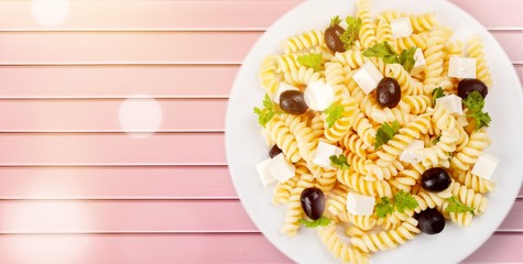 Close-up photo of pasta with olives and cheese in white plate