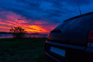 Obraz premium black car on the beach on a beautiful sunset background. sea sunrise view from car on the beach. ocean vacation and ocean holiday.