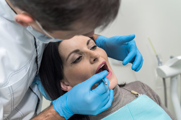 Doctor inspecting patient's teeth with mirror close up