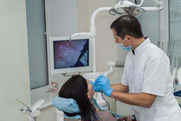 Dentist checking patient's teeth with camera in stomatology