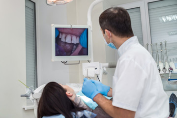 Obraz premium Dentist checking patient's teeth with camera, looking on screen