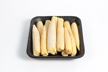 Close up baby corn in foam pack supermarket isolated on white background, copy space 