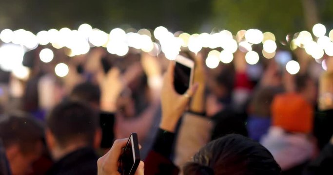 A blurred view of many bright smartphone flashlights filling outdoors