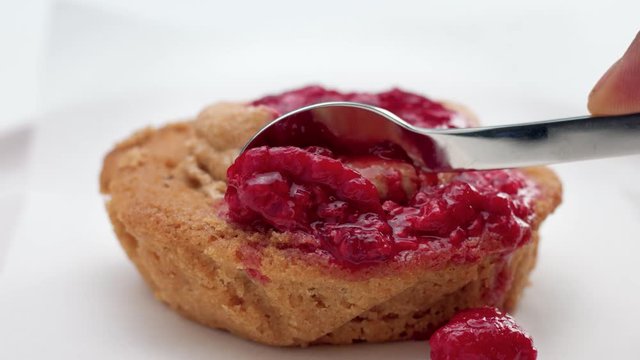 small cake with red fruit topping and a spoon pick a part of it