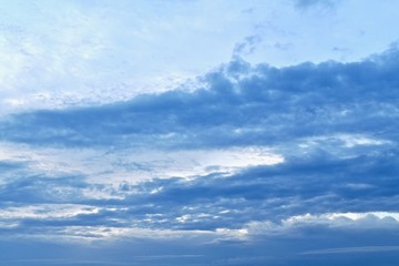 Blue sky with diagonal stripes of blue clouds. From left to right up. Photo with a blue gradient, from light to dark.