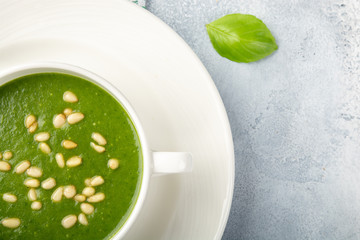 The concept of a healthy, vegetarian or dietary food: cream spinach soup, with pine nuts and basil. With slices of vegetarian carrot bread. On a light background