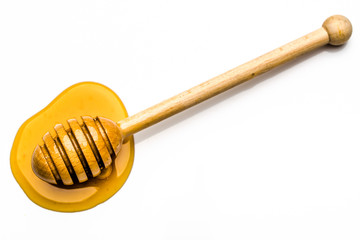 Drop of honey, top view with a wooden honey dipper isolated on white background