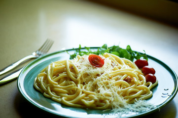 Pasta Carbonara with grated Parmesan cheese and cherry tomatoes, decorated with arugula. Italian lunch.