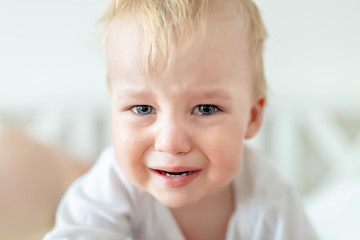Cute caucasian blond toddler boy portrait crying at home during hysterics. Little child feeling...