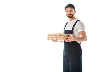 handsome delivery man holding pizza boxes and smiling at camera isolated on white