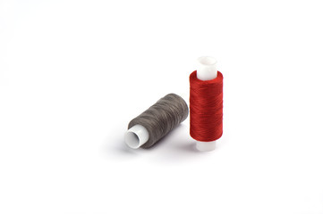 Cotton red and gray threads on the plastic sleeve for the sewing machine.