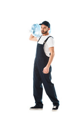 serious delivery man in overalls carrying bottle of water isolated on white