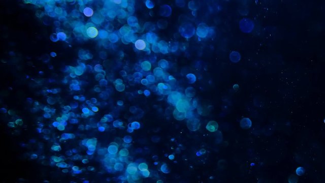 Blue glitter in blur on a black background.