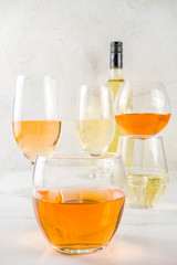 Trendy orange wine, with white wine in different glasses, white concrete background copy space