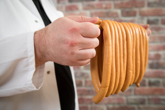 Mann r&auml;uchert Wiener W&uuml;rstchen in Fleischer Manufaktur Produktion 