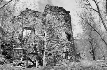 white and black ruins of a stone house of an abandoned village in forest