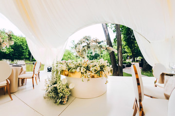 luxury wedding decor. Wedding in white and gold colors. elegant wedding decorated with white flowers. tropical flowers at the wedding. Wedding in a white tent. white table of the bride and groom.