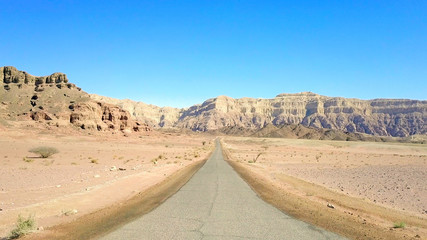 Long stretch of an old Desert road with mountains and blue sky in the background, Aerial image.