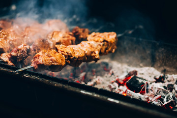 meat on a spit. pork grill. smoking barbecue on the street. cooking chicken shashlik. burning coals.