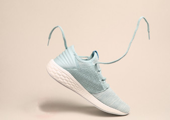 Running sports shoes with flying laces on yellow background.