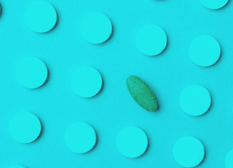 Herbal pill among white chemical pills. Your choice. Background of the group of pills. Medical concept. Duotone effect.