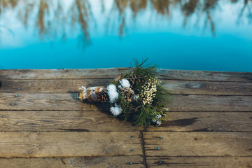 a winter and rustic wedding bouquet on a dock of a lake