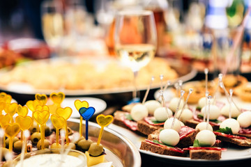 smorgasbord. buffet breakfast. catering services. small sandwiches, cheese and grapes on a skewer, small pies, cherry tomatoes with greens, olive with meat, a cheese plate.