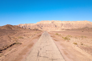 Long stretch of an old Desert road with mountains and blue sky in the background, Aerial image.