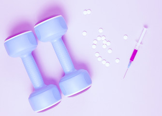Doping in sport. Anabolic steroid. Sports Pharmacy. Plastic dumbbells, syringe, pills on gray background. Duotone effect.
