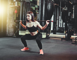 Beautiful fit woman doing squats exercise with gymnastic stick at boxing gym