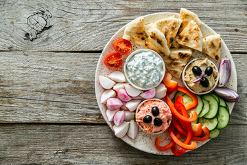 Selection of traditional greek food - salad, meze, pie, fish, tzatziki, dolma on wood background,...