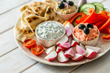 Selection of traditional greek food - salad, meze, pie, fish, tzatziki, dolma on wood background, top view