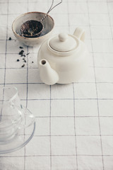 White teapot, cups and strainer on the checkered table cloth