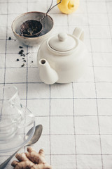 White teapot, cups and strainer on the checkered table cloth
