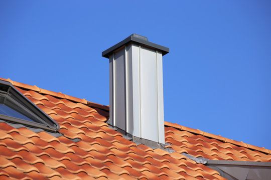 Tiled roof with chimney cladded with stainless steel