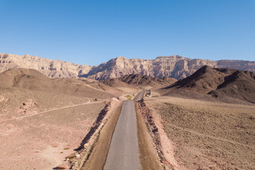 Long stretch of an old Desert road with mountains and blue sky in the background, Aerial image.