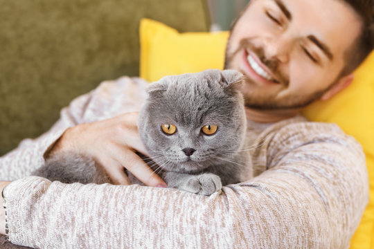 Young man with cute funny cat at home