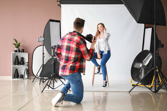 Young male photographer working with model in studio