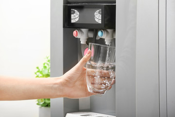 Woman pouring water from cooler into glass, closeup
