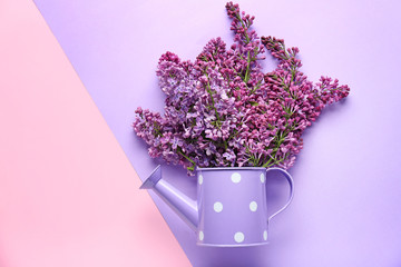 Beautiful lilac flowers and watering can on color background © Pixel-Shot