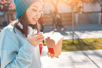 Obraz premium Happy asian woman eaiting takeaway noodles with chopsticks. Chinese fast food concept