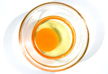 Egg yolk in glass bowl on white background.