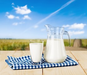 Glass of milk and jug on blurred background