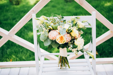 bouquet on a white chair. bouquet of yellow roses, pink chrysanthemums, eucalyptus, poppy head