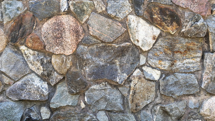 Stone wall. Granite. Colorful granite stone wall. Big rock stones bonded with cement. Grey stone background.