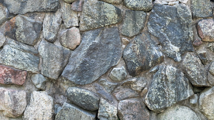 Stone wall. Granite. Colorful granite stone wall. Big rock stones bonded with cement. Grey stone background.