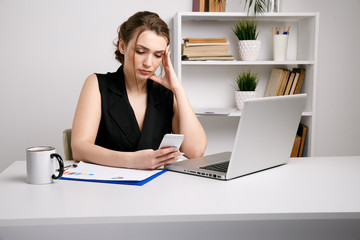 Confused and serious office woman working phone sitting at her desk