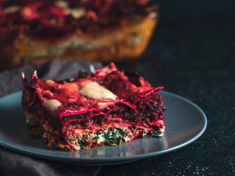 Vegetable Packed Rainbow lasagne on dark background.Ideas and recipes for healthy vegetarian dinner or lunch.Lasagne with beetroot, pumpkin, mushrooms, ricotta, spinach, mozarella. Copy space for text
