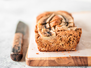 Butter-free, sugar-free banana bread with oat flour, soft curd cheese and honey.Side view of sliced banana bread on wooden cutting board.Copy space.Ideas recipe healthy diet breakfast. Selective focus