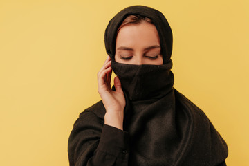 Studio frame of young charming arabian lady  wearing yashmak looking down over isolated background